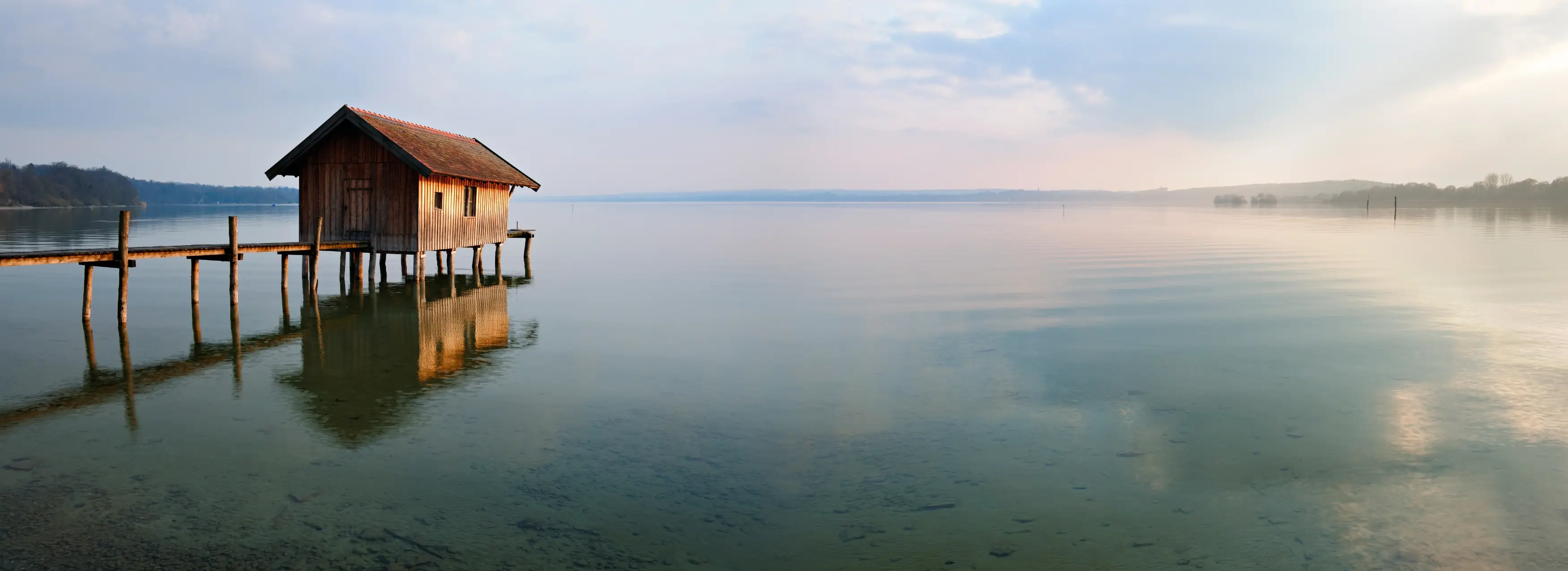 Bootshaus mit Steg im stillen Ammersee bei Abendlicht